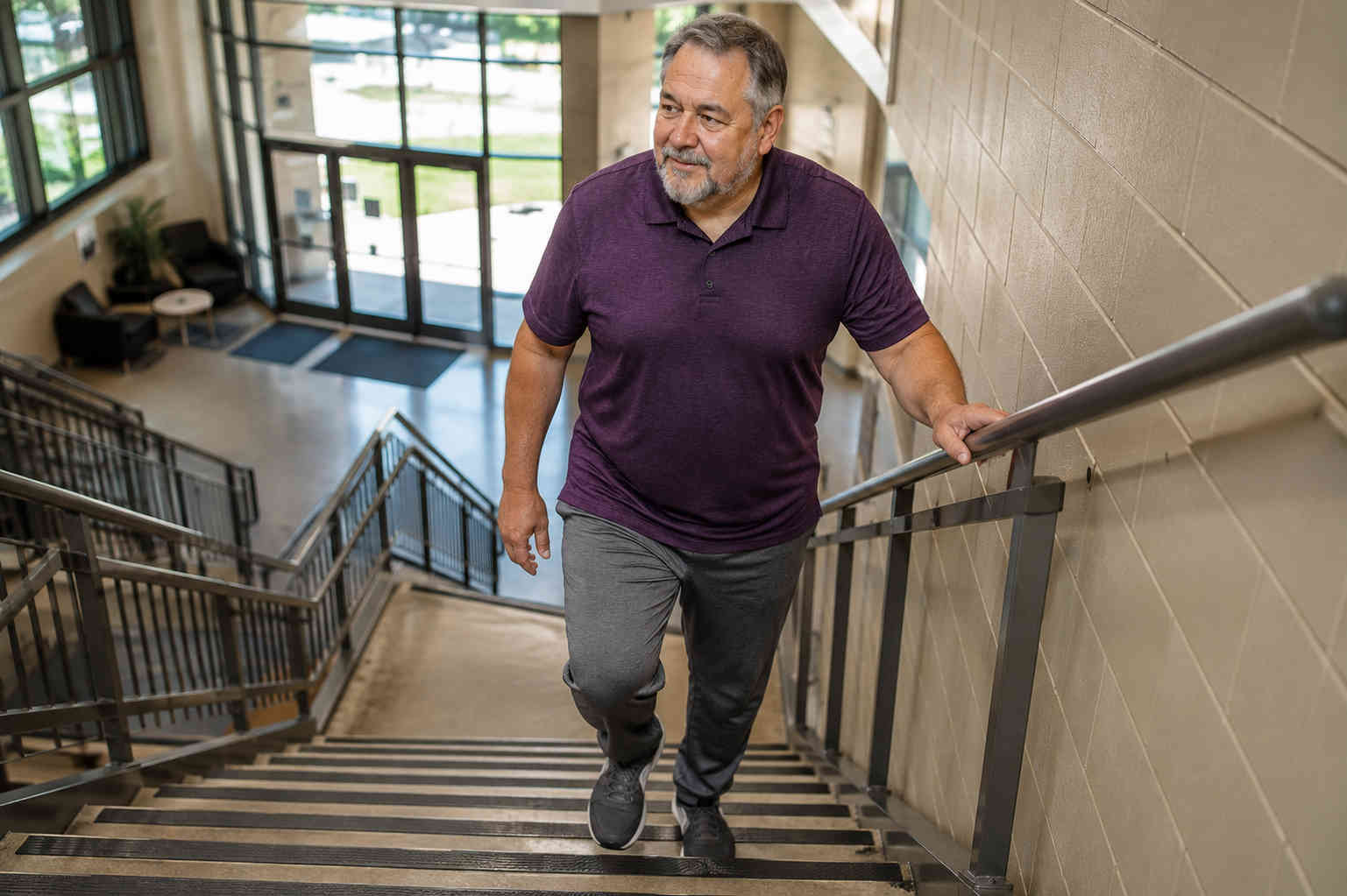 Overweight older man climbing stairs more comfortably after several weeks of beginner exercise