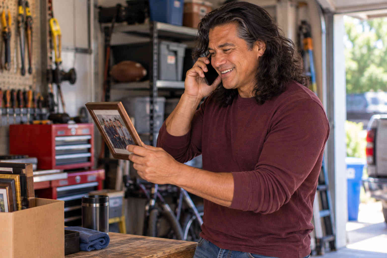 Man in his garage calling an old friend after finding a group photograph