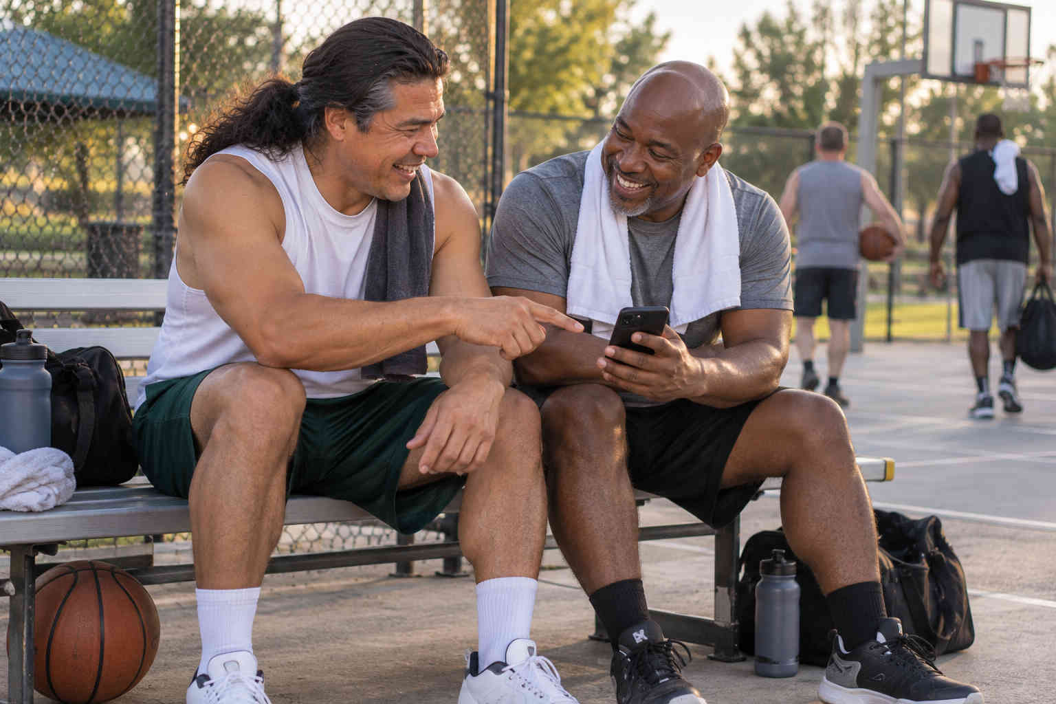Two men laughing and exchanging contact information after a basketball game
